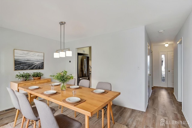 dining space with visible vents, baseboards, and wood finished floors