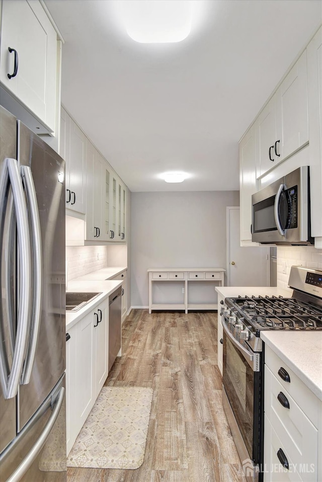 kitchen featuring light wood-style flooring, appliances with stainless steel finishes, white cabinetry, and light countertops