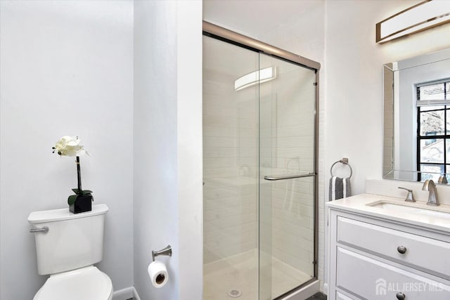 bathroom with vanity, a shower stall, and toilet