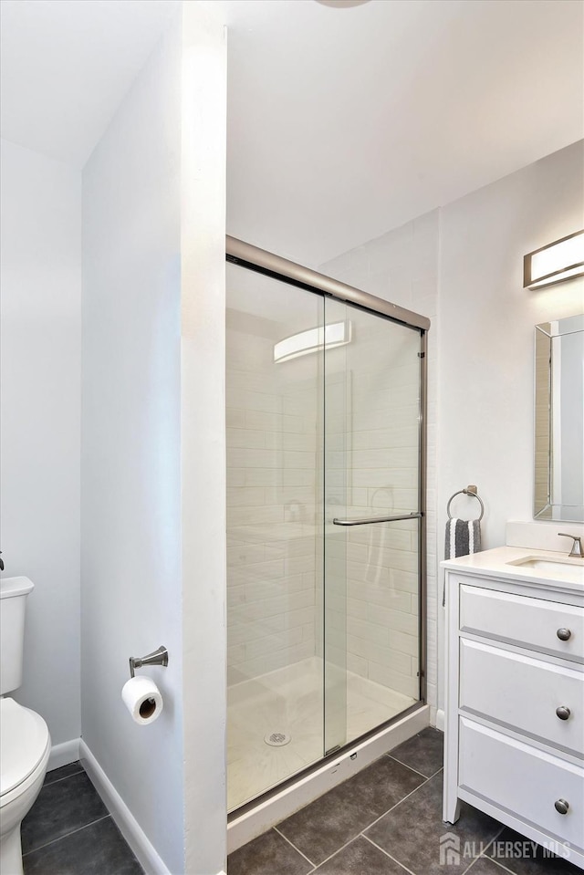 bathroom featuring vanity, a shower stall, toilet, and tile patterned floors