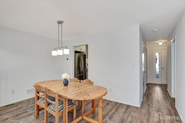 dining room featuring baseboards, visible vents, and light wood-type flooring