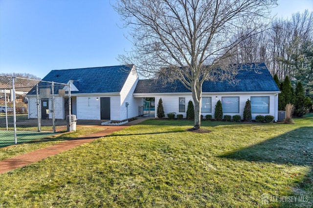 view of front facade featuring a front yard, fence, and roof with shingles