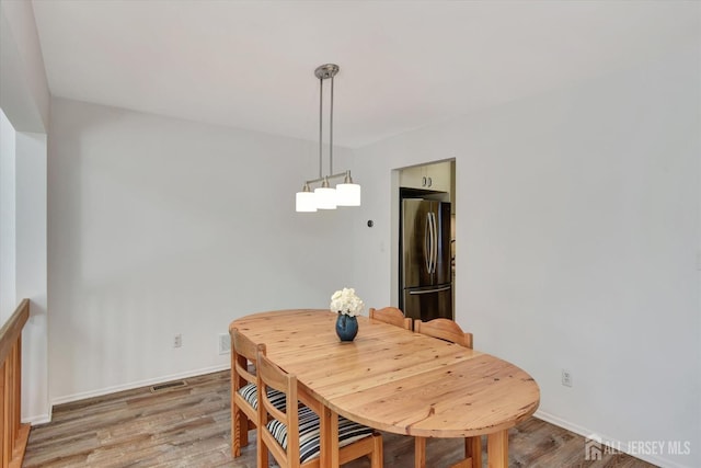 dining space with visible vents, light wood-type flooring, and baseboards