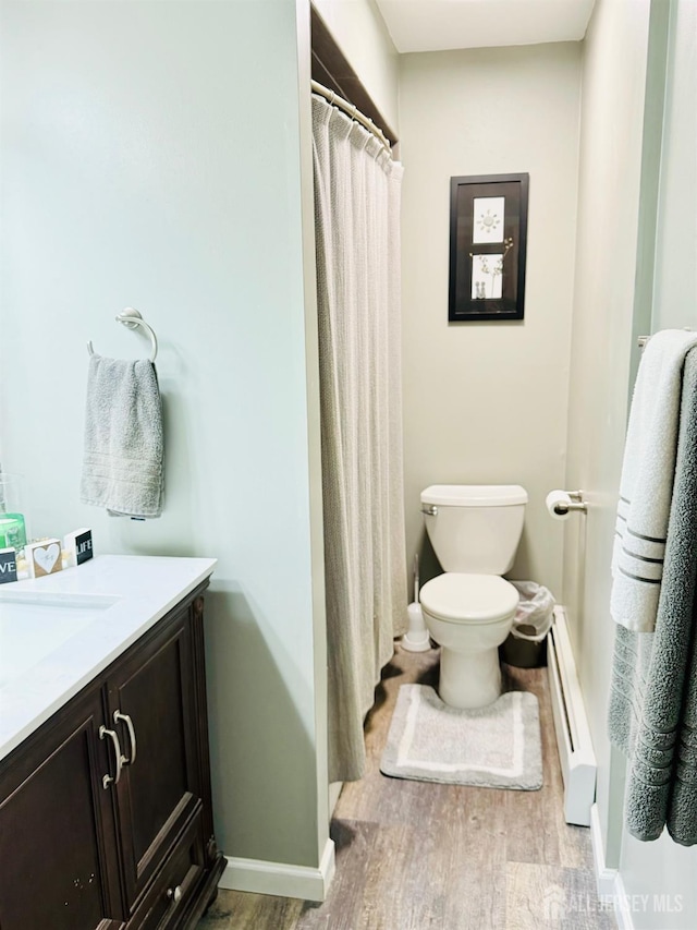 bathroom with a baseboard radiator, baseboards, toilet, and wood finished floors