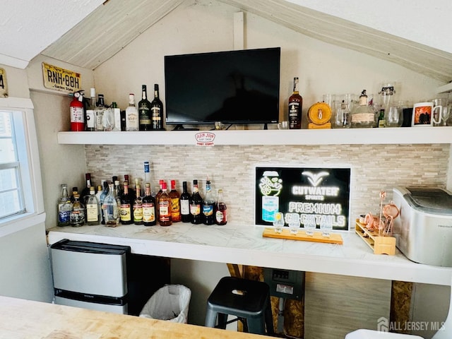 indoor dry bar with lofted ceiling and tasteful backsplash