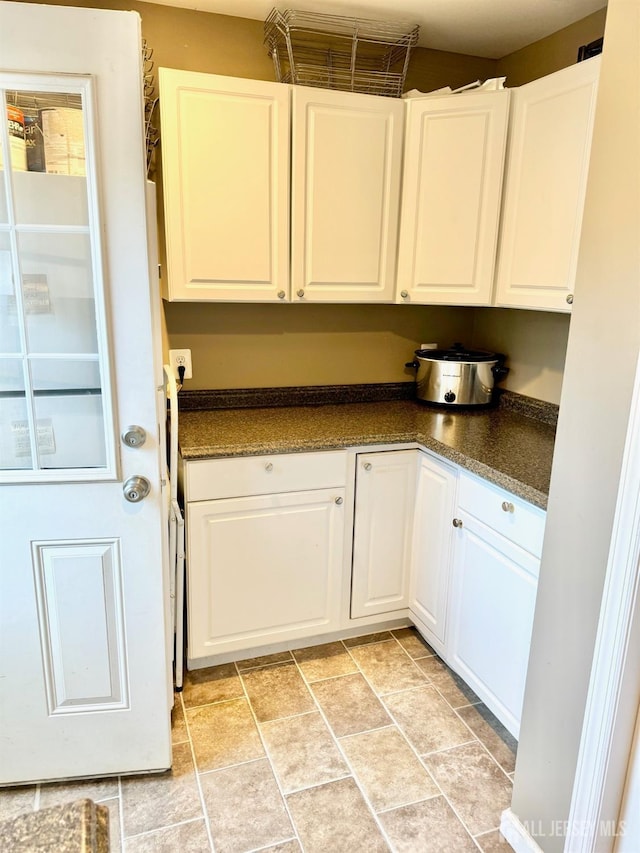 kitchen featuring dark countertops and white cabinetry