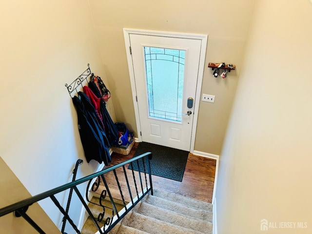 entryway with wood finished floors, baseboards, and stairs