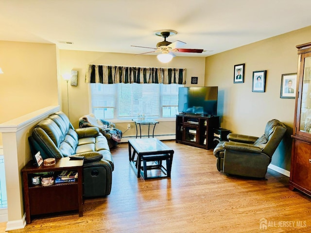 living room with wood finished floors, ceiling fan, baseboard heating, and baseboards