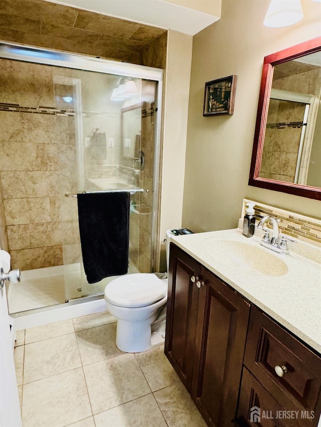 bathroom with vanity, toilet, a shower stall, and tile patterned floors