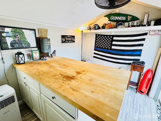bar area with a textured ceiling, wood finished floors, and vaulted ceiling