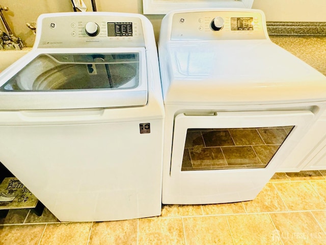 clothes washing area featuring washer and clothes dryer and tile patterned flooring