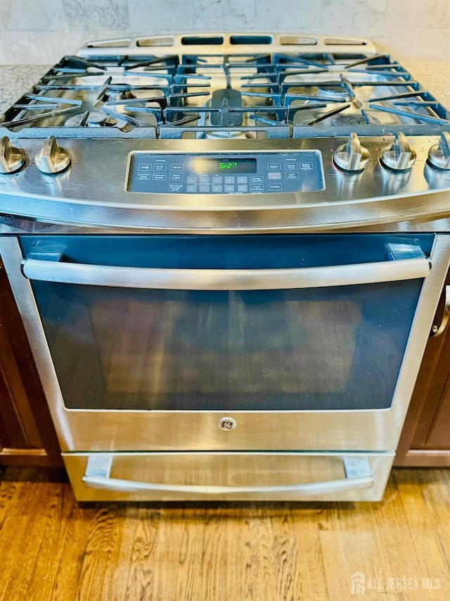 kitchen view of stainless steel range with gas stovetop and tasteful backsplash