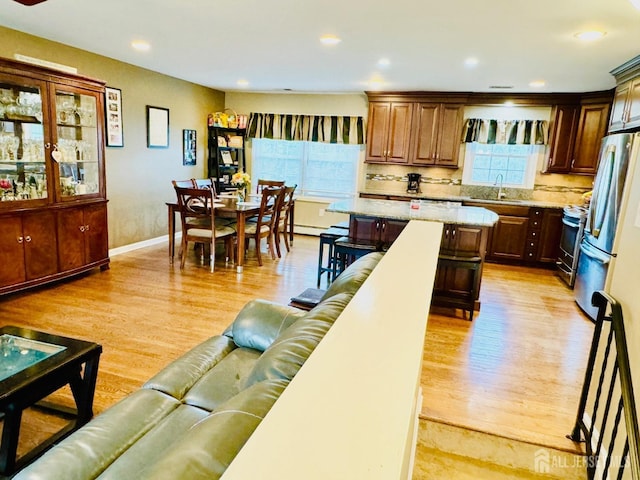 living room with healthy amount of natural light, light wood-type flooring, recessed lighting, and baseboards