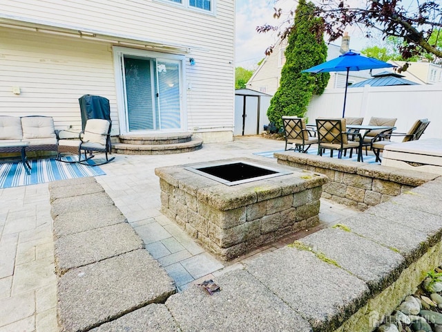 view of patio / terrace featuring a shed, an outbuilding, fence, and an outdoor living space with a fire pit