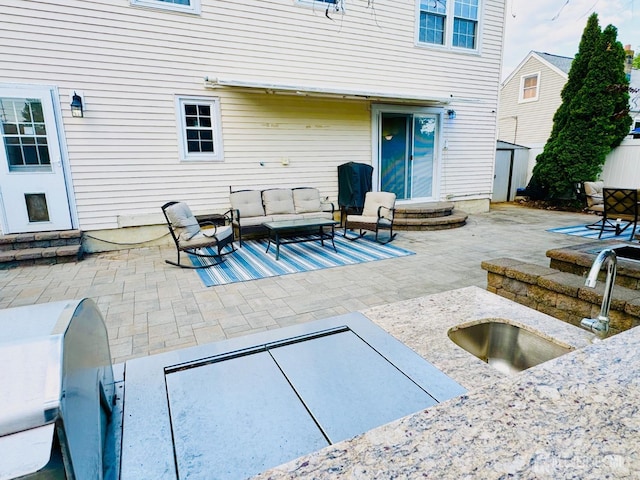 view of patio / terrace featuring a sink, outdoor lounge area, a storage unit, and an outdoor structure
