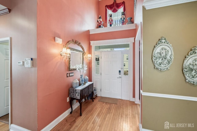 entrance foyer featuring baseboards, light wood-style floors, and a high ceiling