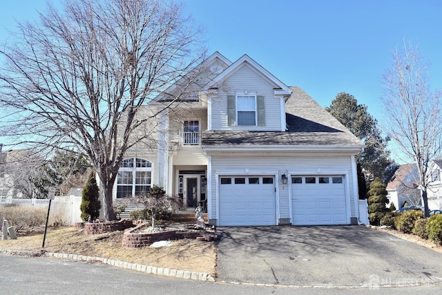 traditional-style house with aphalt driveway, fence, a shingled roof, and a garage