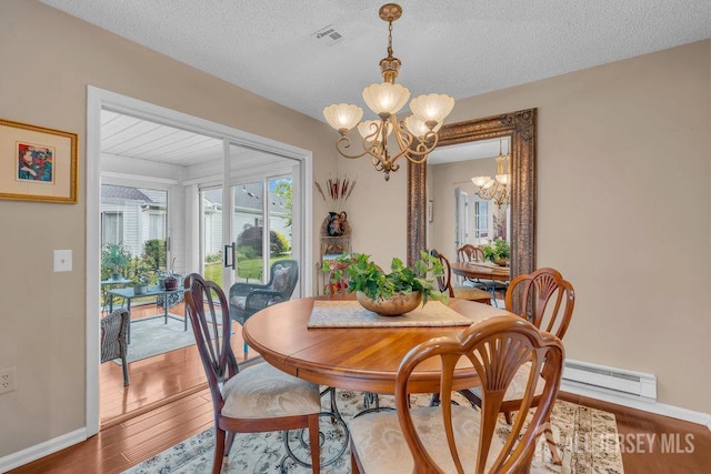 539 Old Nassau Rd Unit B, Monroe, NJ 08831 - dining room featuring a chandelier, baseboard heating, wood finished floors, baseboards, and a textured ceiling
