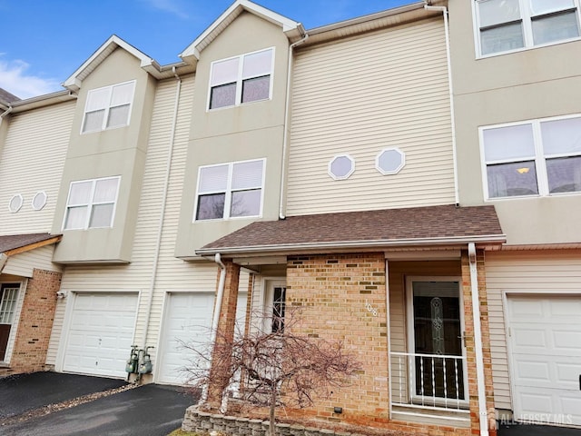 townhome / multi-family property featuring a garage, driveway, and brick siding