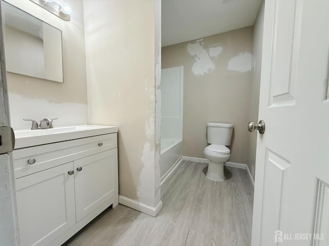 full bath featuring toilet, baseboards, wood finished floors, and vanity