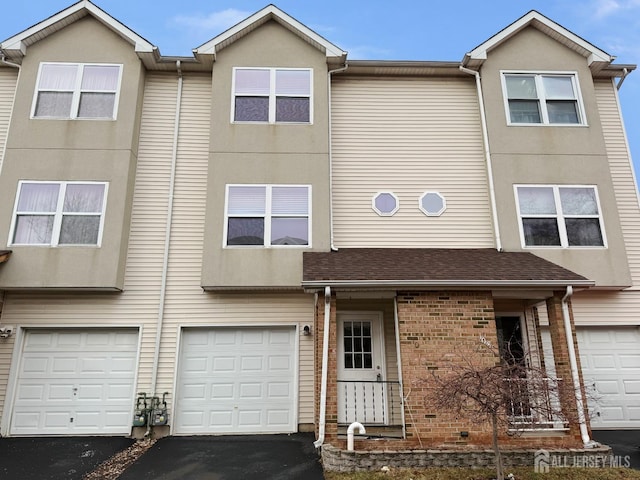 multi unit property featuring an attached garage and driveway