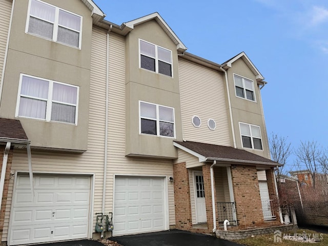 view of property with covered porch, an attached garage, driveway, and stucco siding