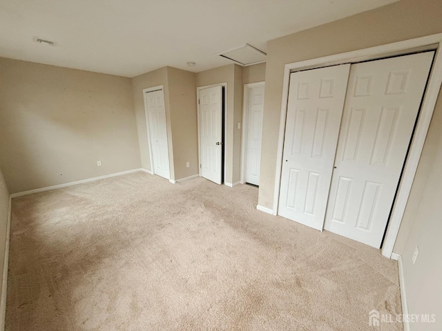 unfurnished bedroom featuring baseboards, light carpet, and two closets