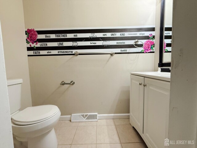 bathroom featuring visible vents, vanity, toilet, baseboards, and tile patterned floors