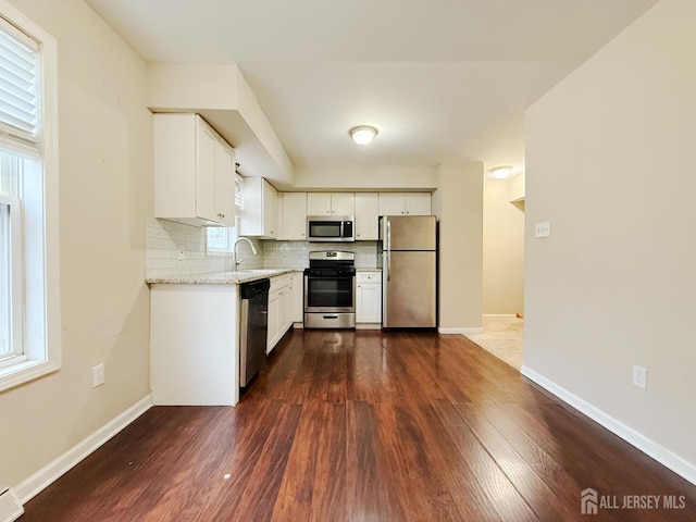 kitchen with a sink, appliances with stainless steel finishes, dark wood-style flooring, and light stone counters