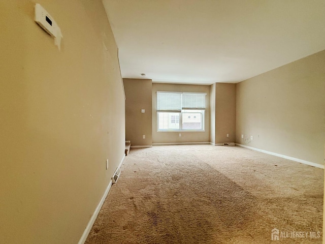 spare room featuring visible vents, carpet flooring, and baseboards
