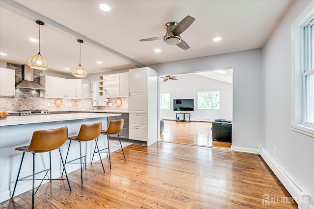 878 Beatrice Pkwy, Edison, NJ 08820 - kitchen with a baseboard heating unit, wall chimney exhaust hood, a kitchen breakfast bar, decorative backsplash, and light countertops