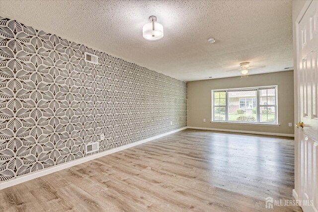922 Thomas Ave, North Brunswick, NJ 08902 - spare room featuring a textured ceiling, wood finished floors, baseboards, a ceiling fan, and brick wall
