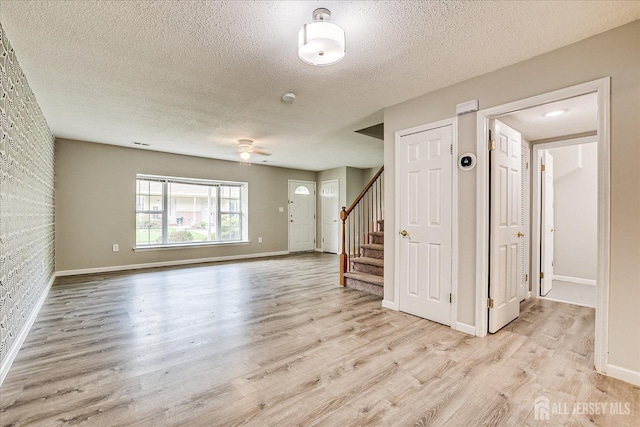 922 Thomas Ave, North Brunswick, NJ 08902 - unfurnished living room featuring light wood-style flooring, stairs, a textured ceiling, baseboards, and a ceiling fan