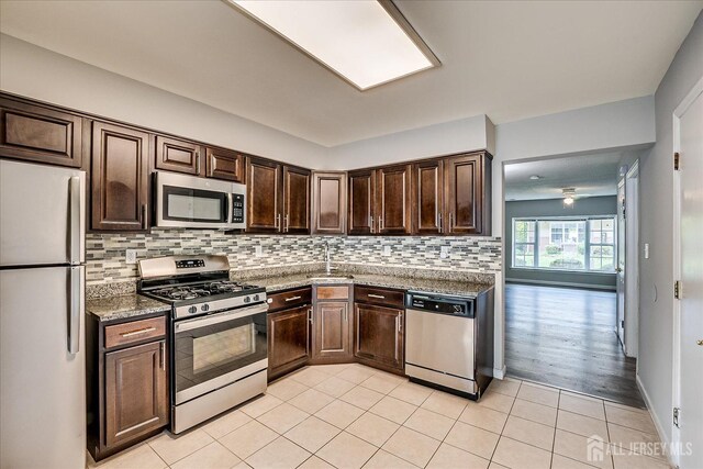 922 Thomas Ave, North Brunswick, NJ 08902 - kitchen with stainless steel appliances, dark brown cabinetry, tasteful backsplash, light tile patterned flooring, and a sink