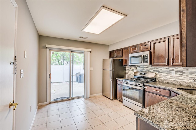 922 Thomas Ave, North Brunswick, NJ 08902 - kitchen featuring stainless steel appliances, tasteful backsplash, baseboards, light tile patterned floors, and stone counters