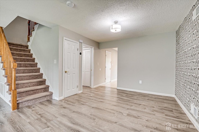 922 Thomas Ave, North Brunswick, NJ 08902 - unfurnished living room with light wood-style flooring, stairs, a textured ceiling, and baseboards