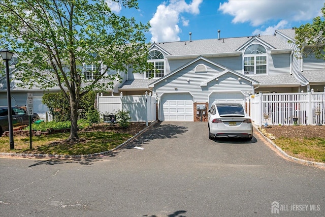 922 Thomas Ave, North Brunswick, NJ 08902 - view of front facade with driveway, fence, a garage, and roof with shingles