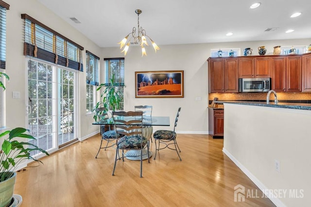 dining area with an inviting chandelier, sink, and light hardwood / wood-style flooring