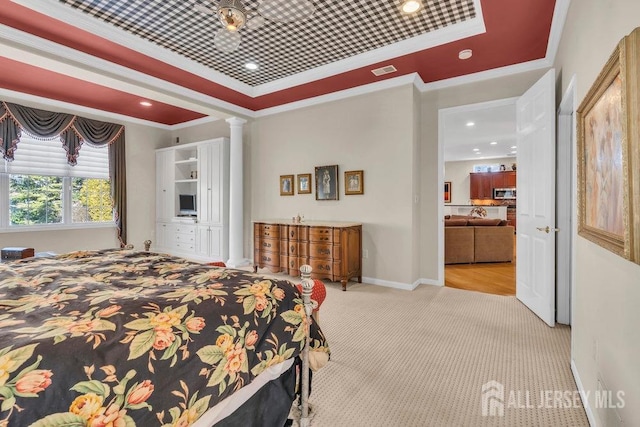 carpeted bedroom featuring ornamental molding, a tray ceiling, and ornate columns