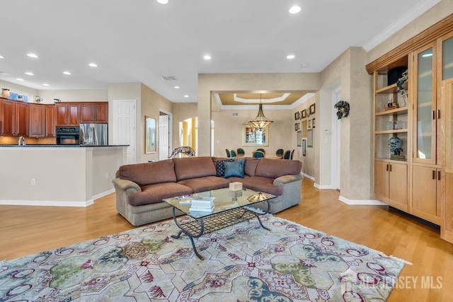 living room with sink, light hardwood / wood-style flooring, and ornamental molding