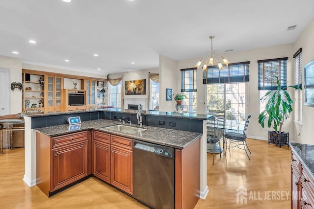 kitchen featuring pendant lighting, sink, dark stone countertops, black dishwasher, and an inviting chandelier