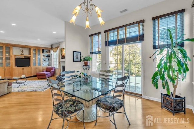 dining room with an inviting chandelier, light hardwood / wood-style floors, built in features, and a wealth of natural light