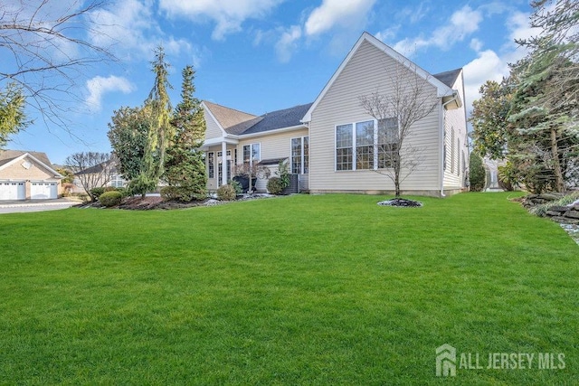 back of property with a garage and a lawn