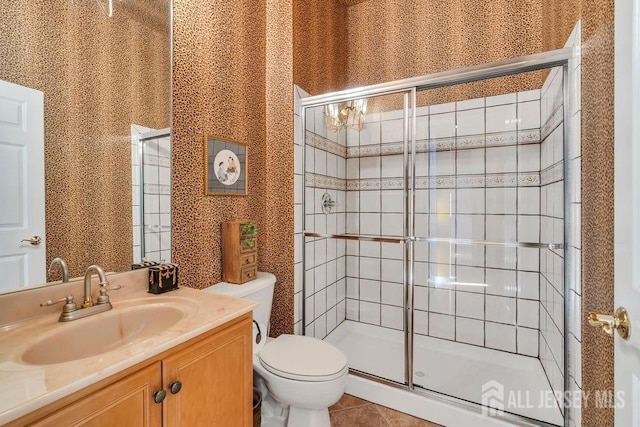 bathroom featuring walk in shower, vanity, toilet, and tile patterned flooring