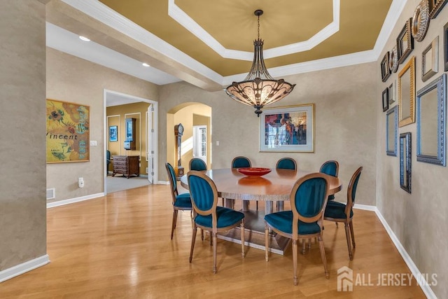 dining room featuring a notable chandelier, a tray ceiling, ornamental molding, and hardwood / wood-style flooring