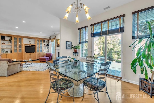 dining space featuring a chandelier, light hardwood / wood-style floors, and built in features