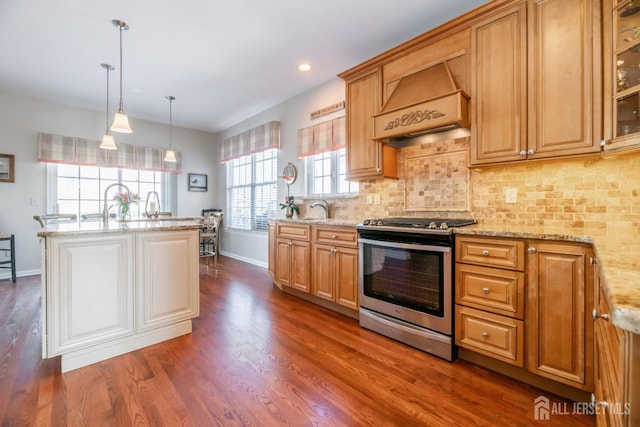 kitchen with premium range hood, dark hardwood / wood-style floors, decorative light fixtures, light stone countertops, and stainless steel range oven