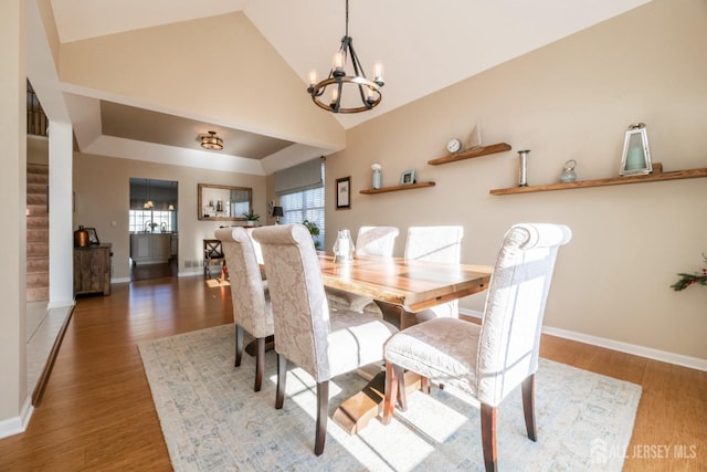 dining space featuring dark hardwood / wood-style flooring, high vaulted ceiling, and a chandelier