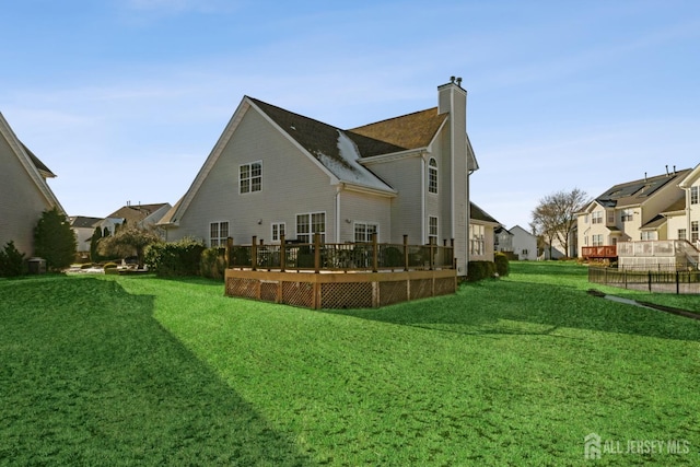 rear view of property featuring a deck and a lawn