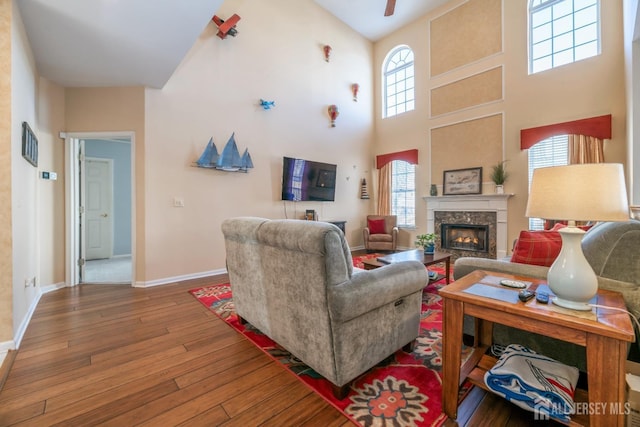 living room featuring hardwood / wood-style floors, ceiling fan, and a high ceiling